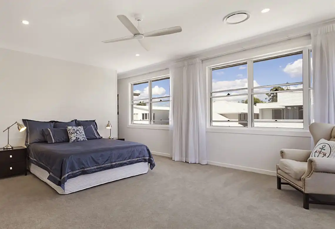 Two white double hung windows in a bedroom